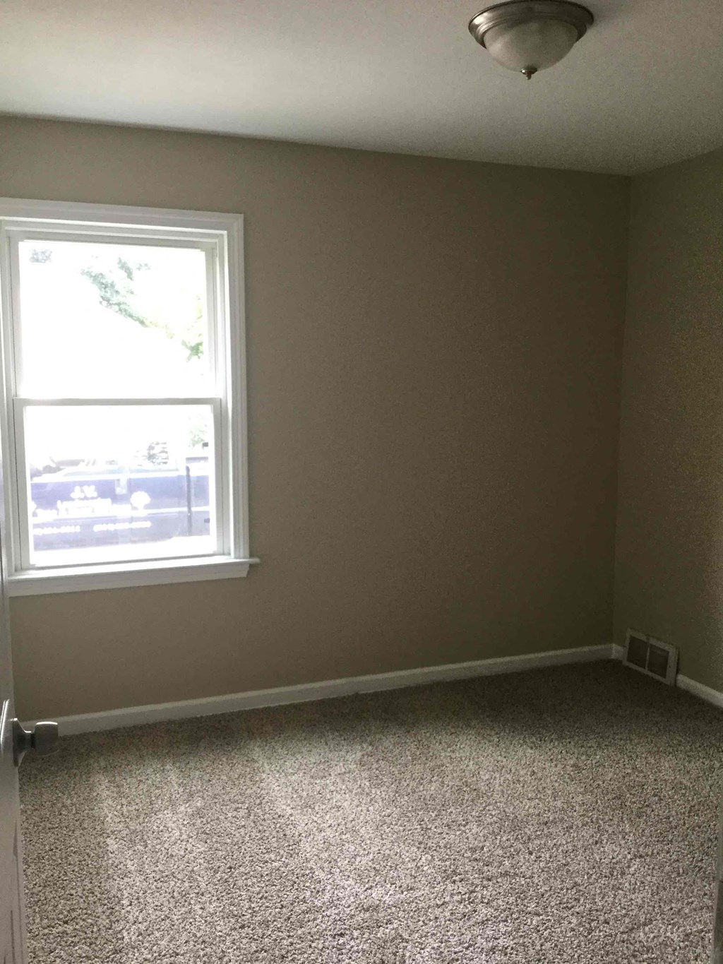 A room with a window and carpeted floor.