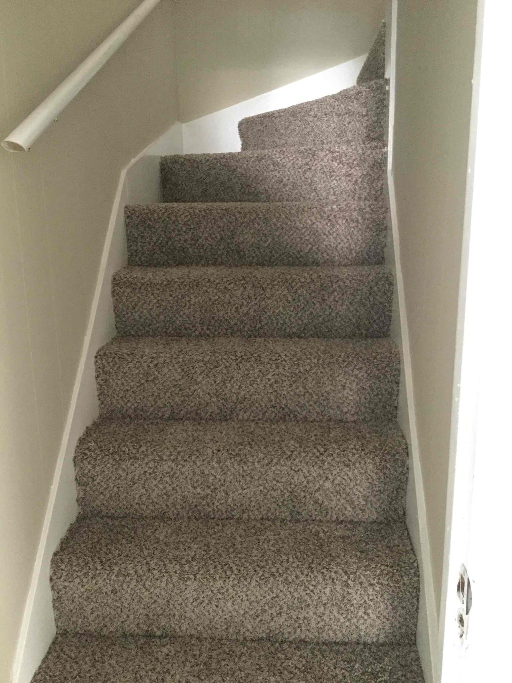 A staircase with a carpeted runner and white walls.