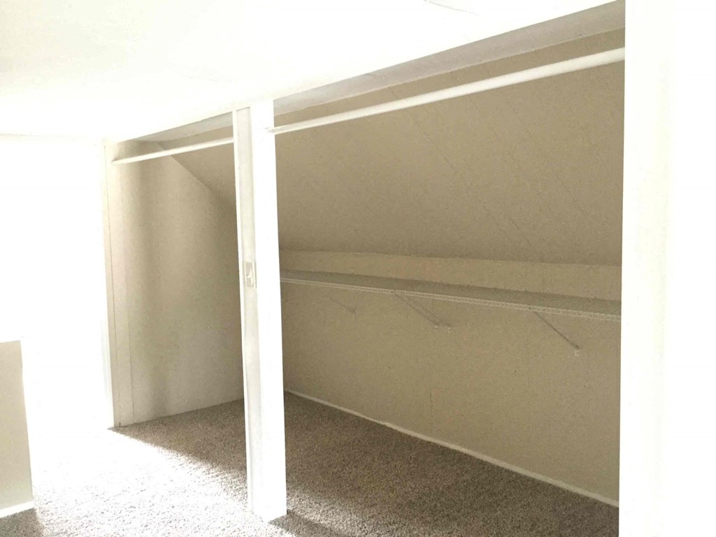 A white bed with a white mattress is in a room with a carpet.