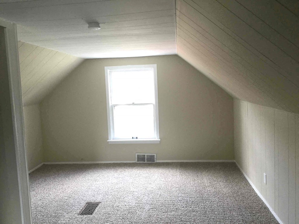 A room with a window and a carpeted floor.