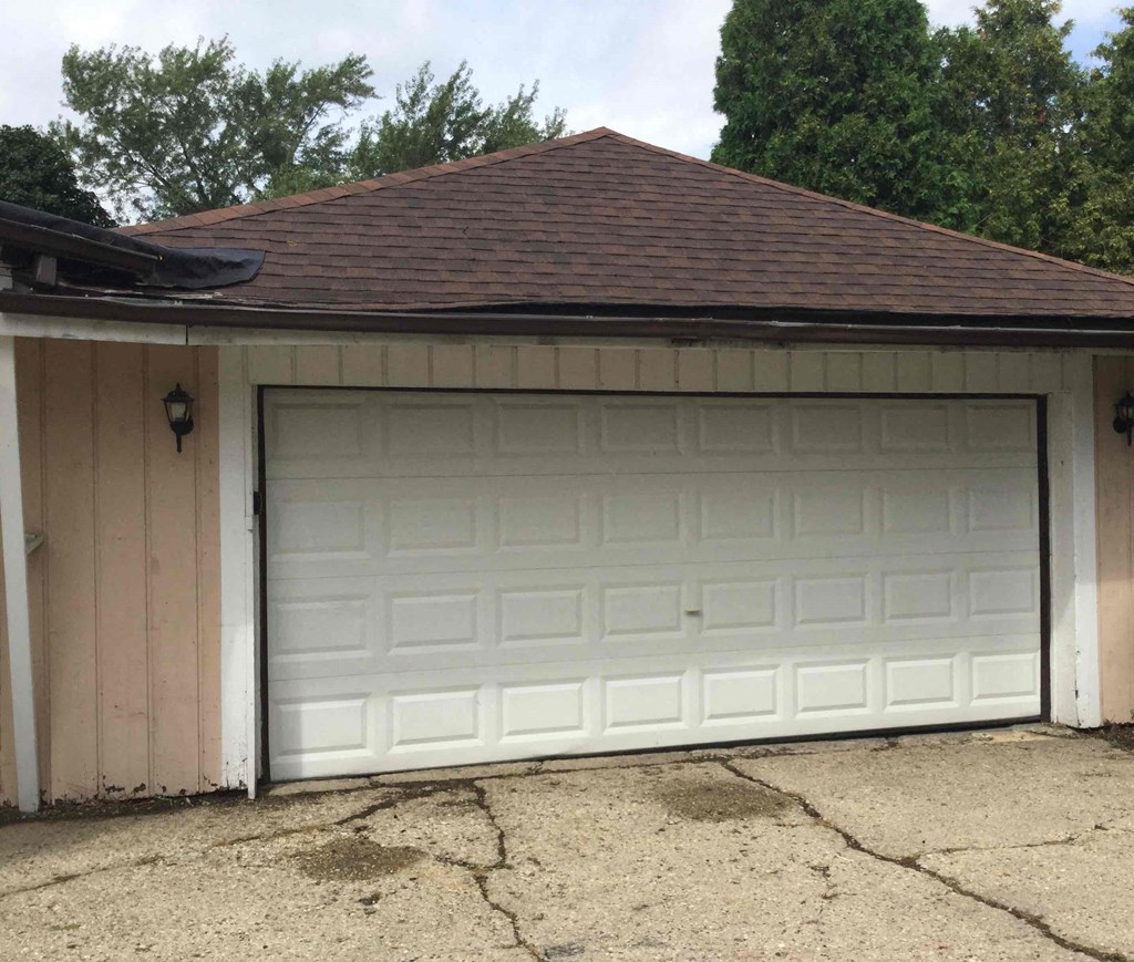 A white garage door is closed and the garage is attached to a house.