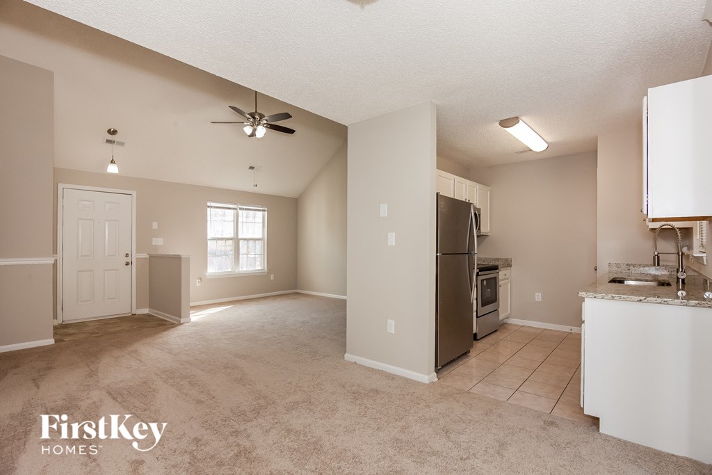 an empty kitchen and living room with a stainless steel refrigerator
