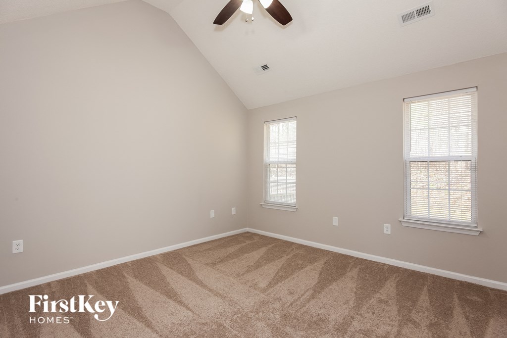the spacious living room with two windows and a ceiling fan