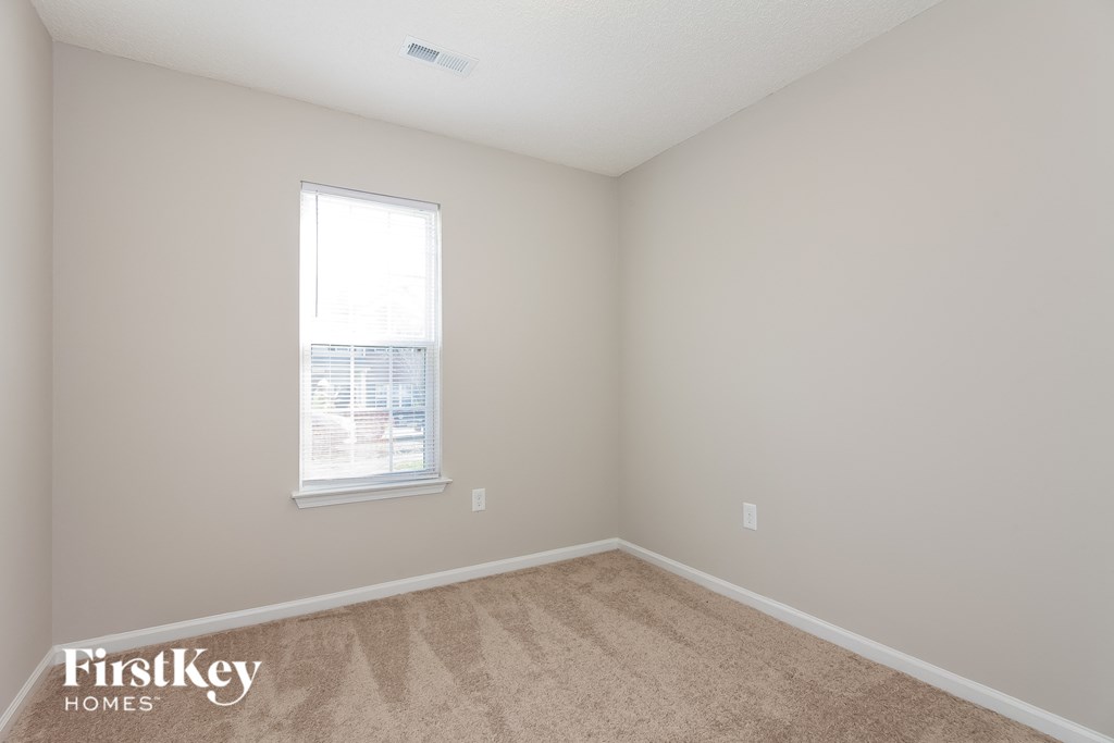 a bedroom with a window and a carpeted floor