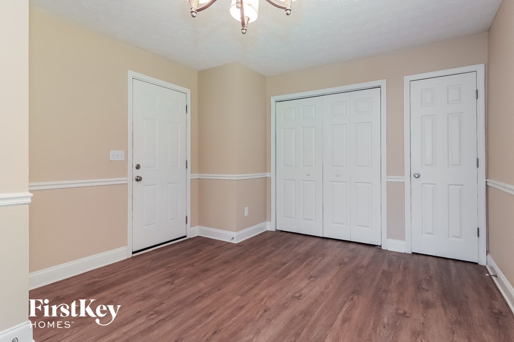the living room of a home with three doors and a wood floor
