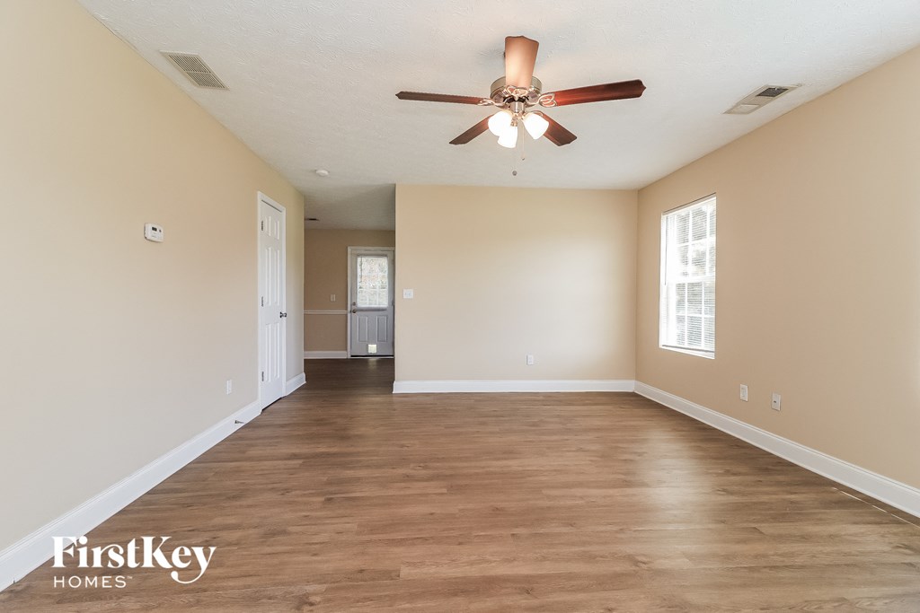 an empty living room with a ceiling fan and white walls