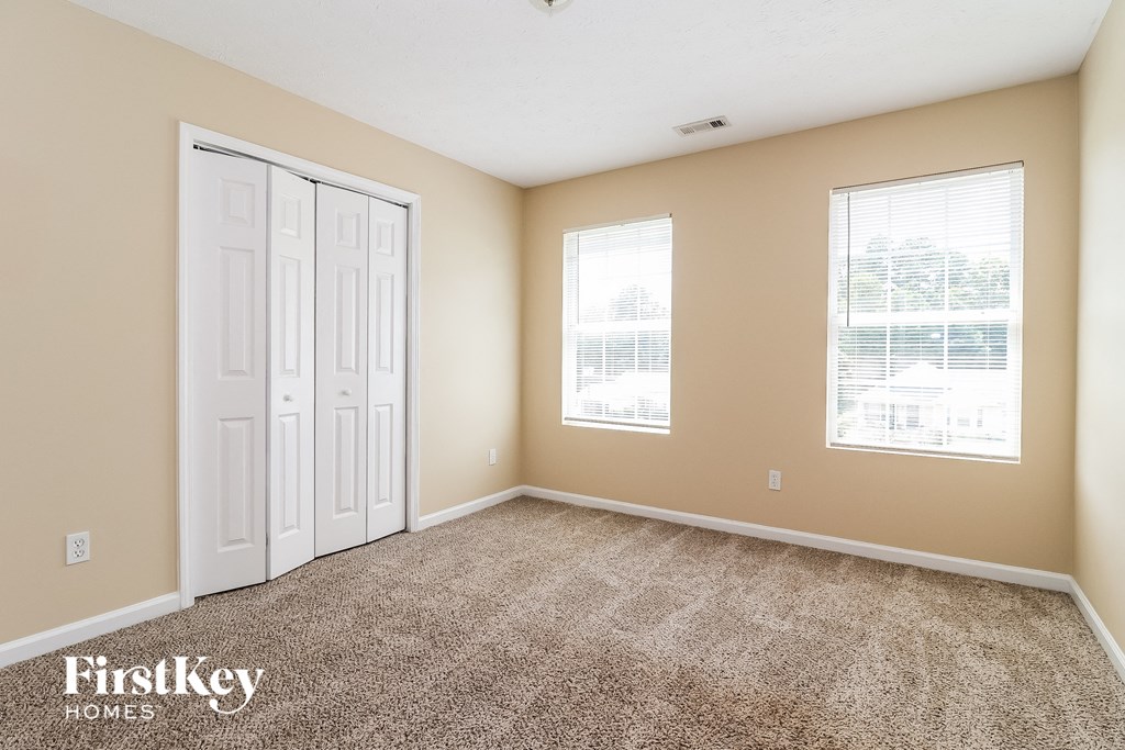 a room with carpet and two windows and a white door
