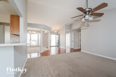 A spacious room with a ceiling fan and a carpeted floor.