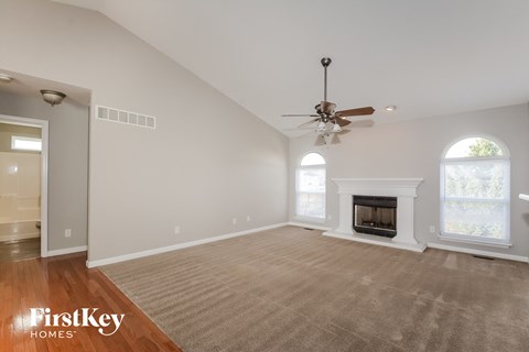 A spacious living room with a fireplace and a ceiling fan.