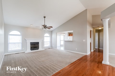 A spacious living room with a fireplace and a ceiling fan.