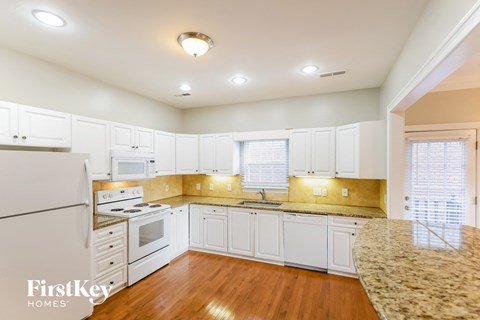 A kitchen with white cabinets and a granite counter top.
