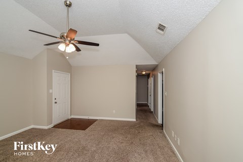a spacious living room with carpet and a ceiling fan