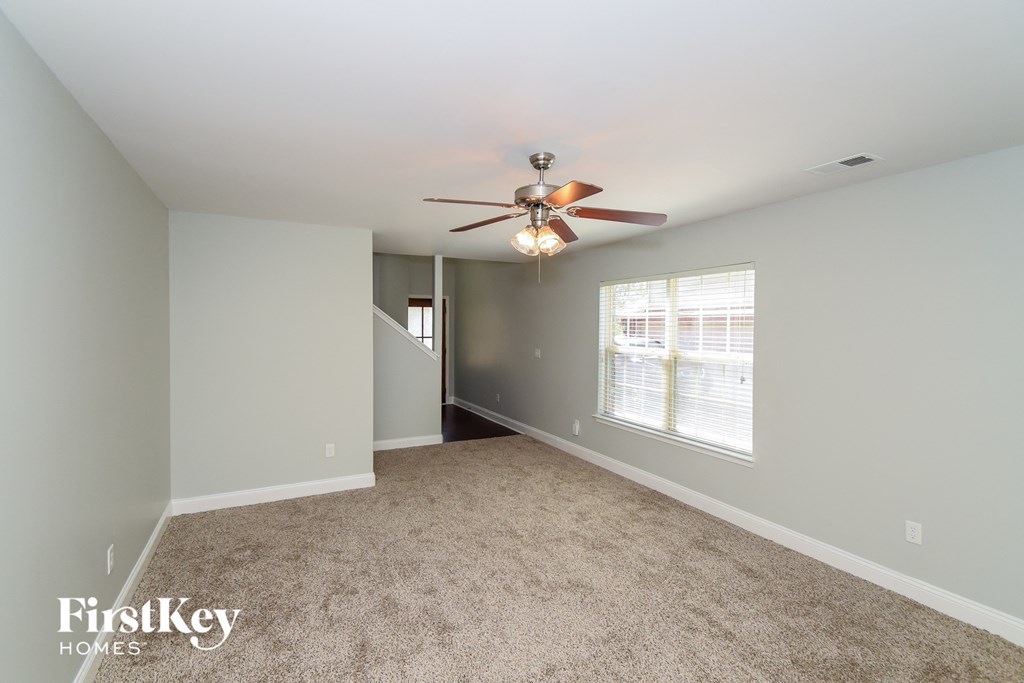 A spacious room with a ceiling fan and carpeted floor.