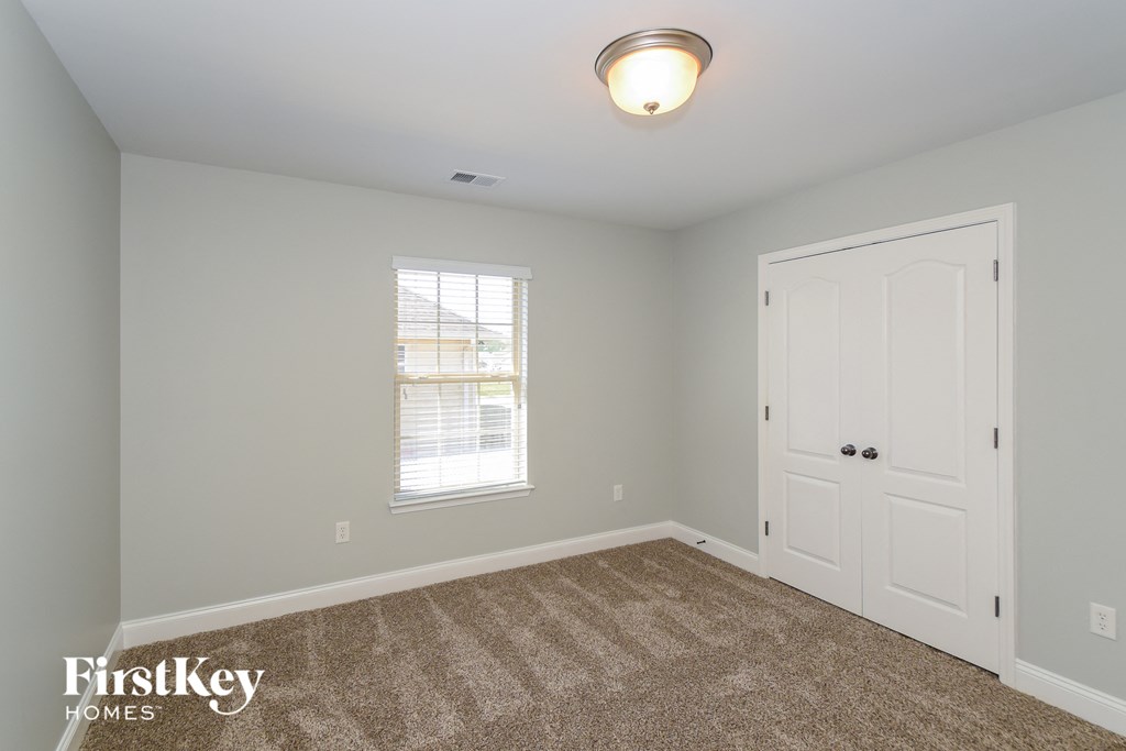 A room with a carpeted floor, a door, and a window.