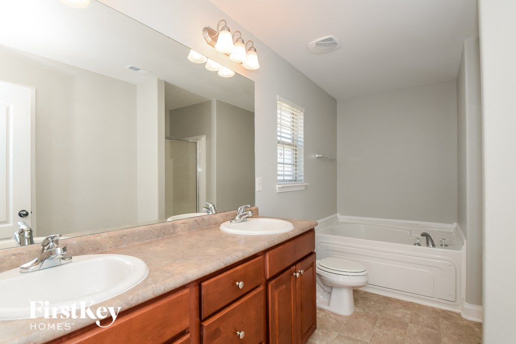 A bathroom with a double sink vanity and a white toilet.