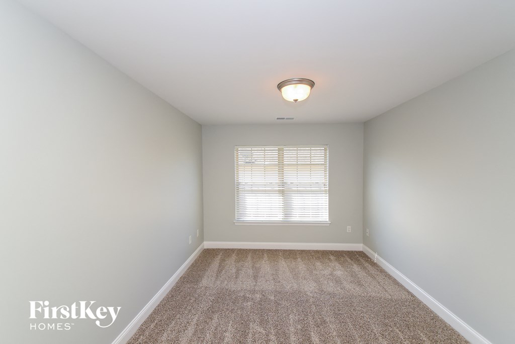 A room with a carpeted floor and a window with blinds.