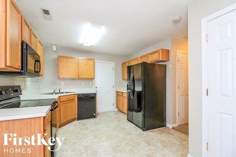 A kitchen with wooden cabinets and a black fridge.