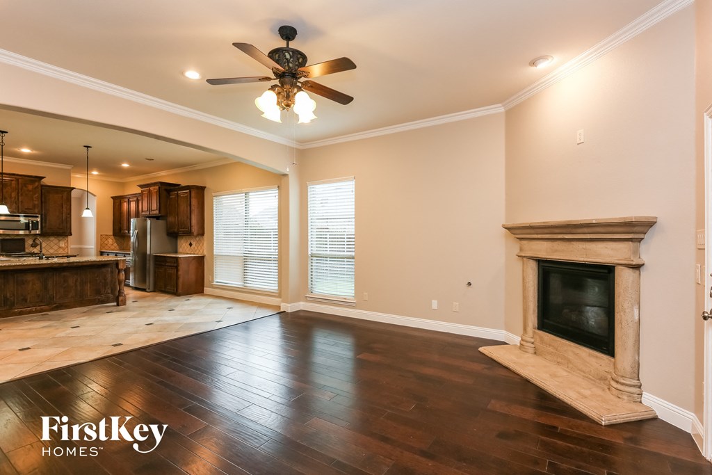 an empty living room with a fireplace and a ceiling fan