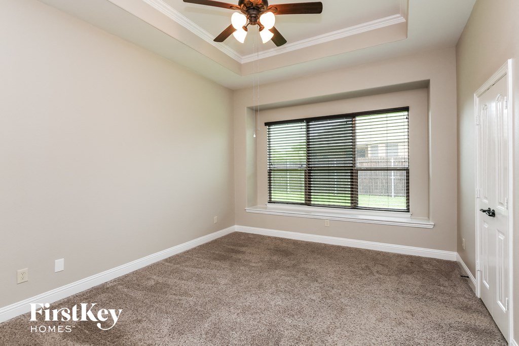 an empty living room with a ceiling fan and a window