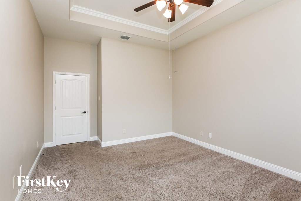 a empty room with a ceiling fan and a white door