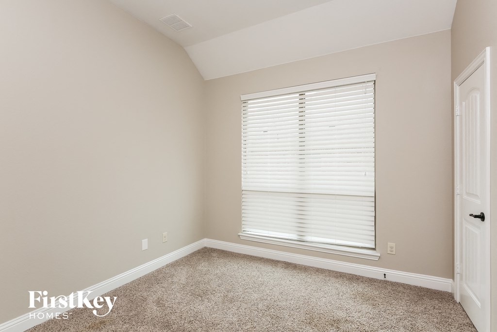 a bedroom with a large window and a carpeted floor