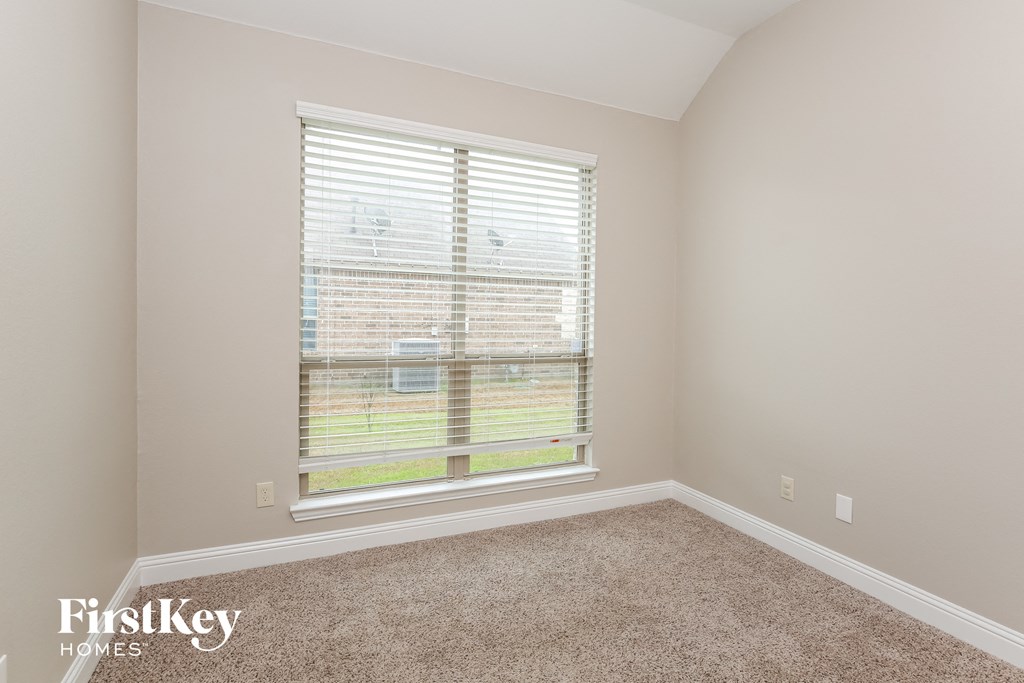 a bedroom with a large window and a carpeted floor