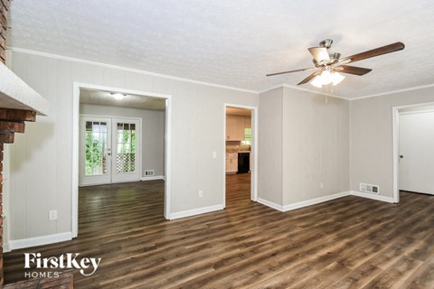 A spacious room with wooden floors and a ceiling fan.