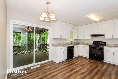 A kitchen with white cabinets and black appliances.