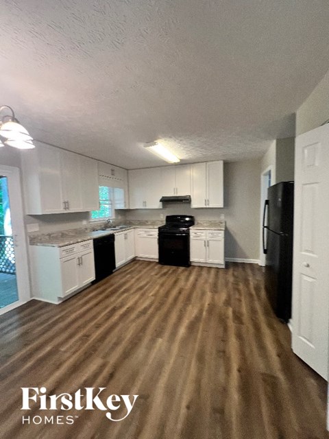 A kitchen with white cabinets and a black refrigerator.