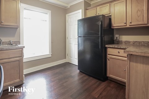 a kitchen with wood floors and a black refrigerator