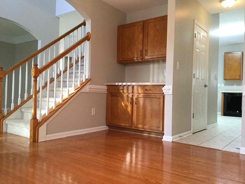 A kitchen with wooden cabinets and a staircase.