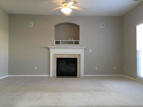 A living room with a fireplace and a ceiling fan.
