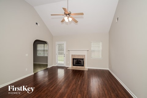 A spacious room with a fireplace and a ceiling fan.