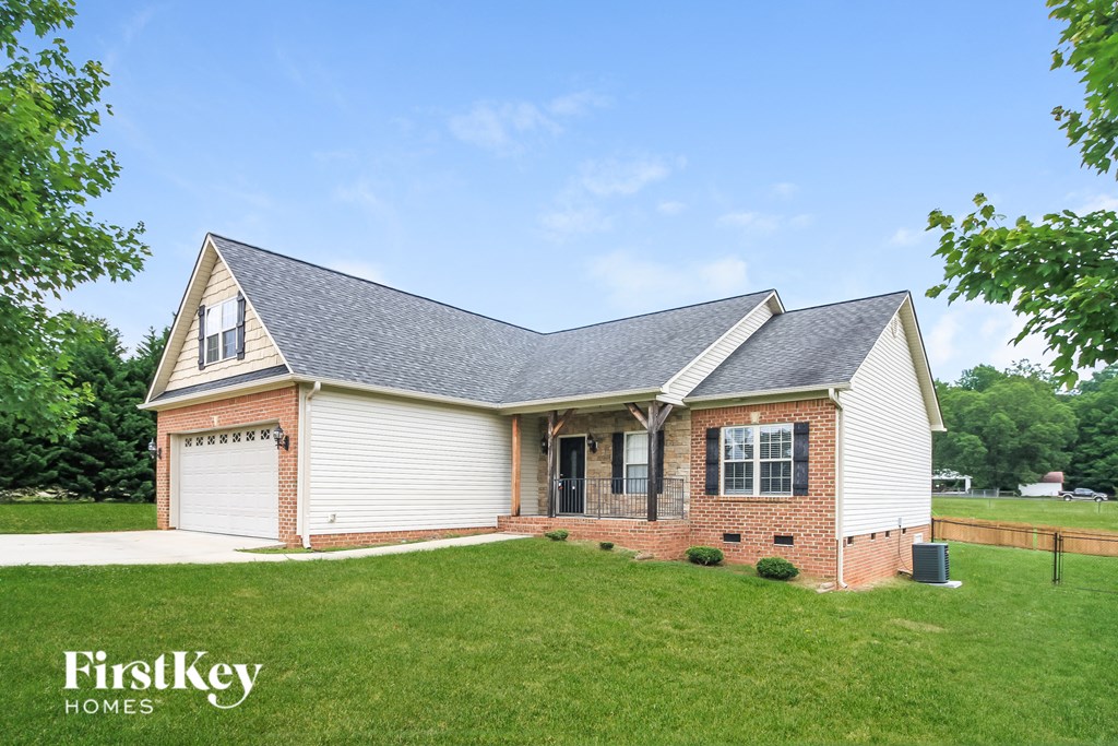 a brick and with a gray roof and a lawn
