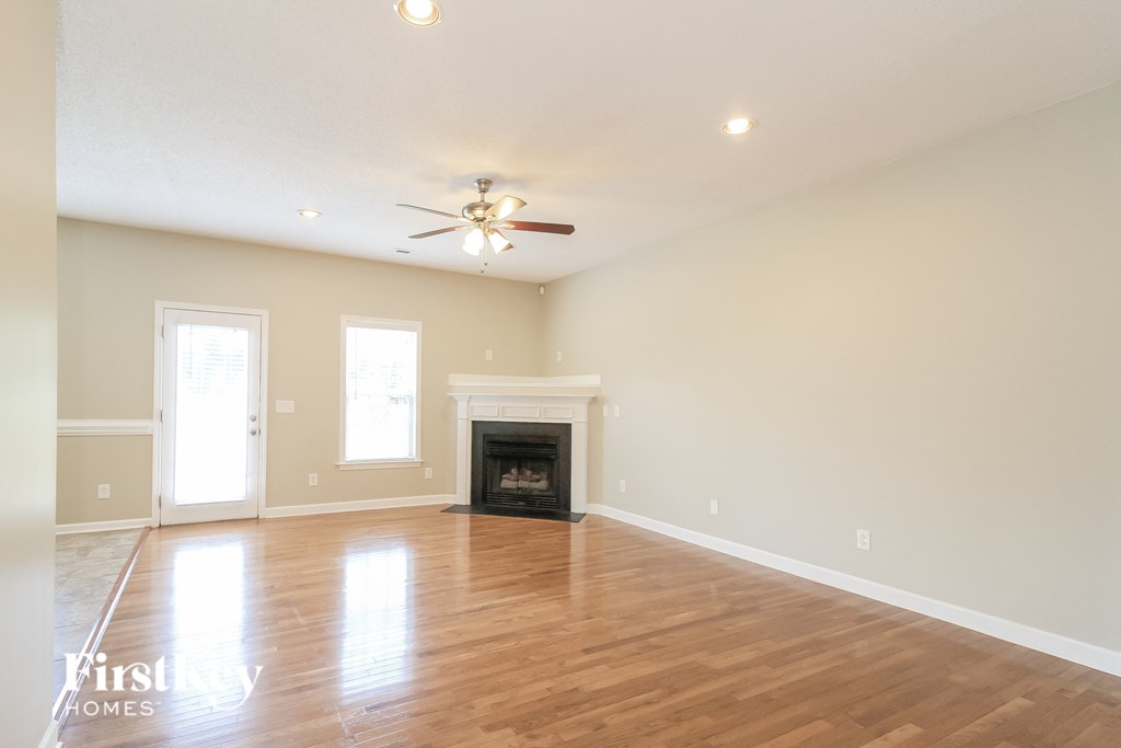 an empty living room with a fireplace and a ceiling fan