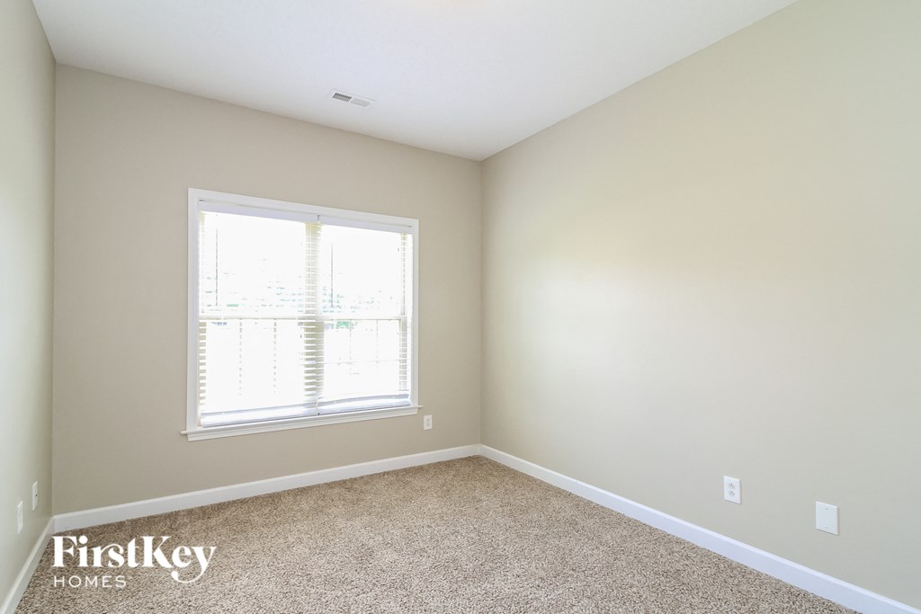 a bedroom with a window and a carpeted floor