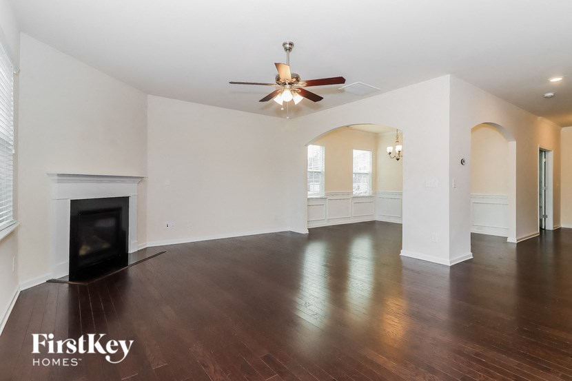 A spacious living room with a fireplace and a ceiling fan.