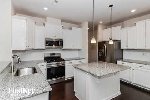 A kitchen with white cabinets and granite countertops.