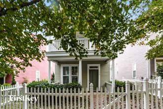 a pink house with a white picket fence and a porch