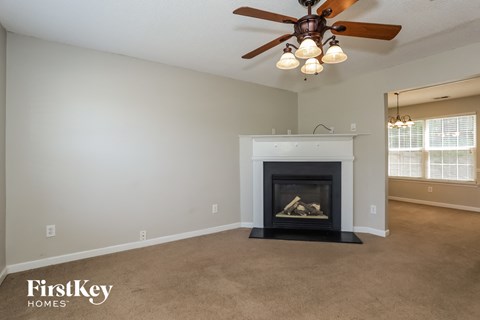 A living room with a fireplace and a ceiling fan.