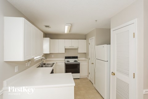 A kitchen with white cabinets and appliances.