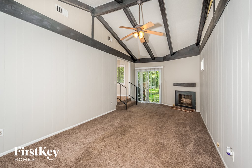 A spacious room with a fireplace and a ceiling fan.