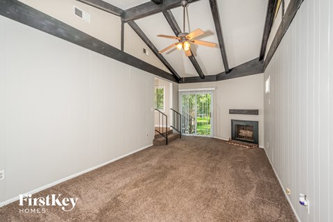 A spacious room with a fireplace and a ceiling fan.
