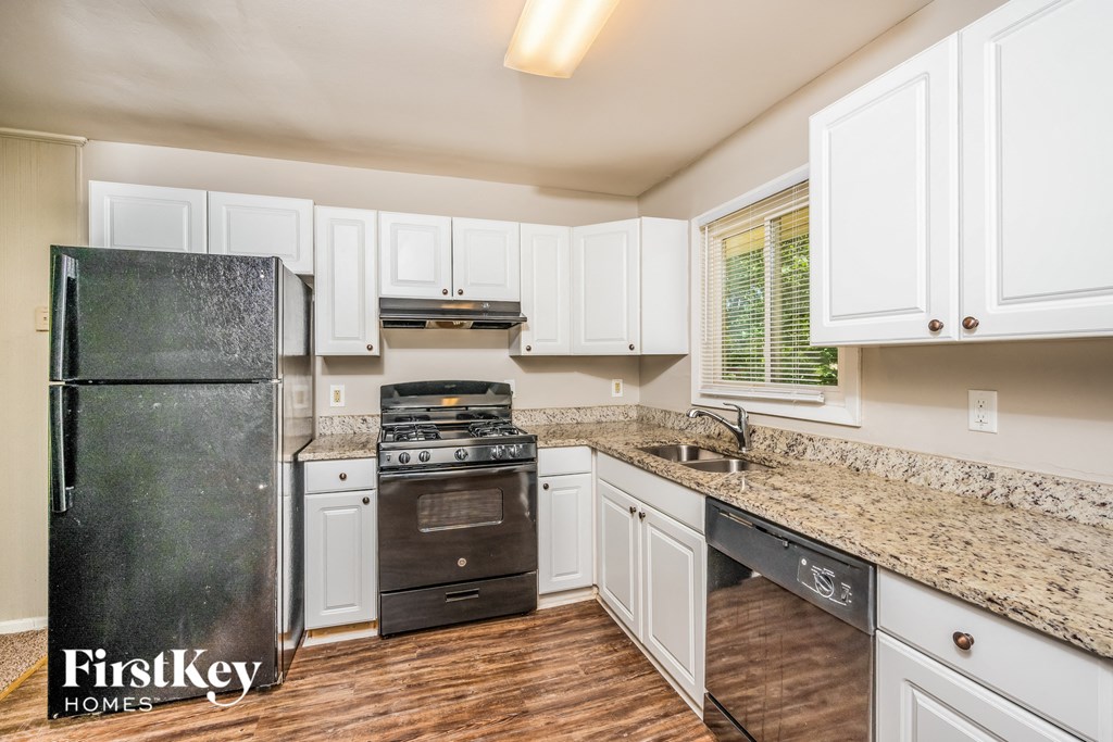 A kitchen with a black fridge and white cabinets.