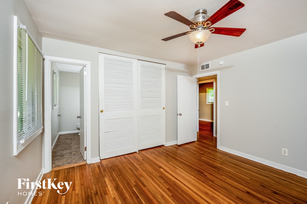 A room with a ceiling fan and wooden floors.