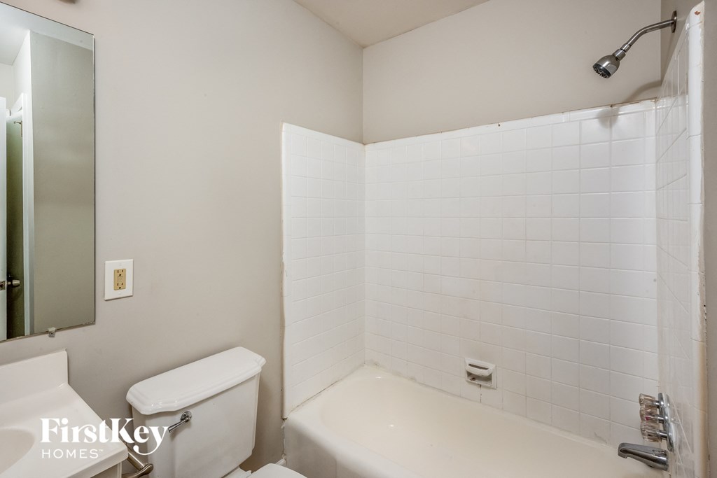 A white tiled bathroom with a toilet, sink, and bathtub.