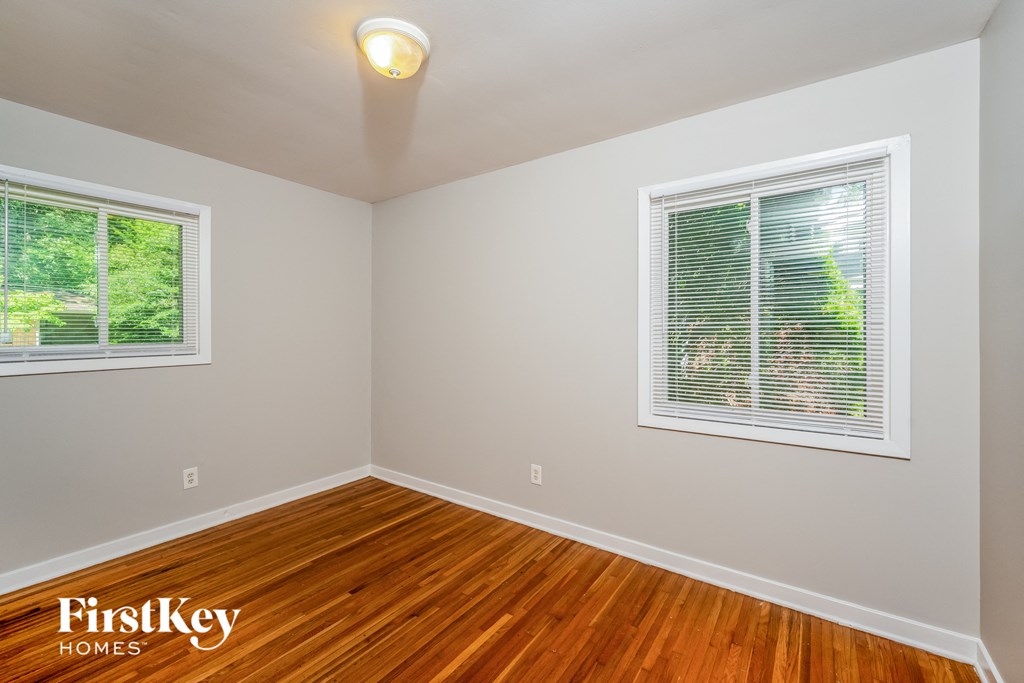 A room with wooden floors and two windows.