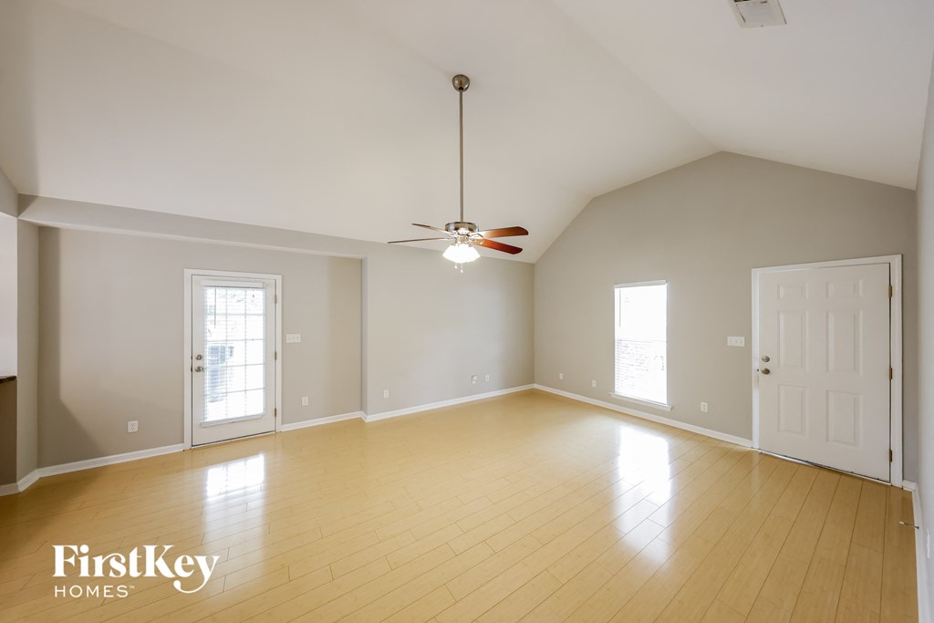A spacious room with a fan and wooden flooring.