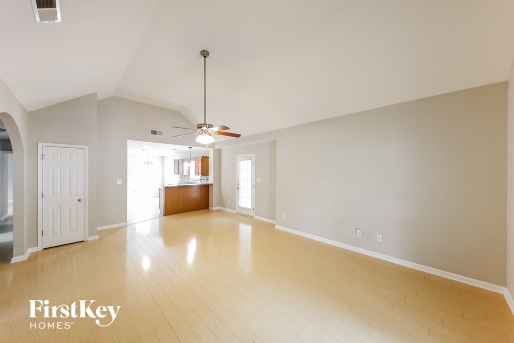 A spacious room with wooden floors and a ceiling fan.