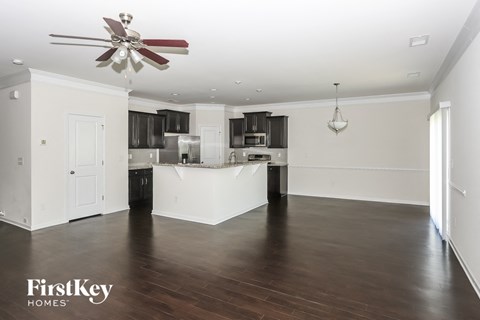 A spacious kitchen and living room with a ceiling fan and hardwood floors.